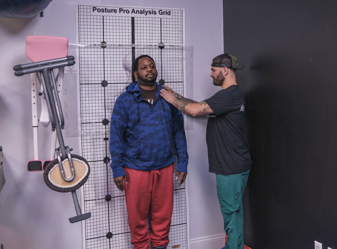This image shows Conrad, lead practitioner at Truly Heal Wellness in Akron, Ohio, conducting a clinical posture and movement assessment. Using his expertise in orthopedic massage and corrective exercise, Conrad evaluates spinal alignment, joint mobility, and muscular imbalances to guide personalized treatment plans. The setting reflects a functional wellness space focused on pain relief, recovery, and performance optimization.