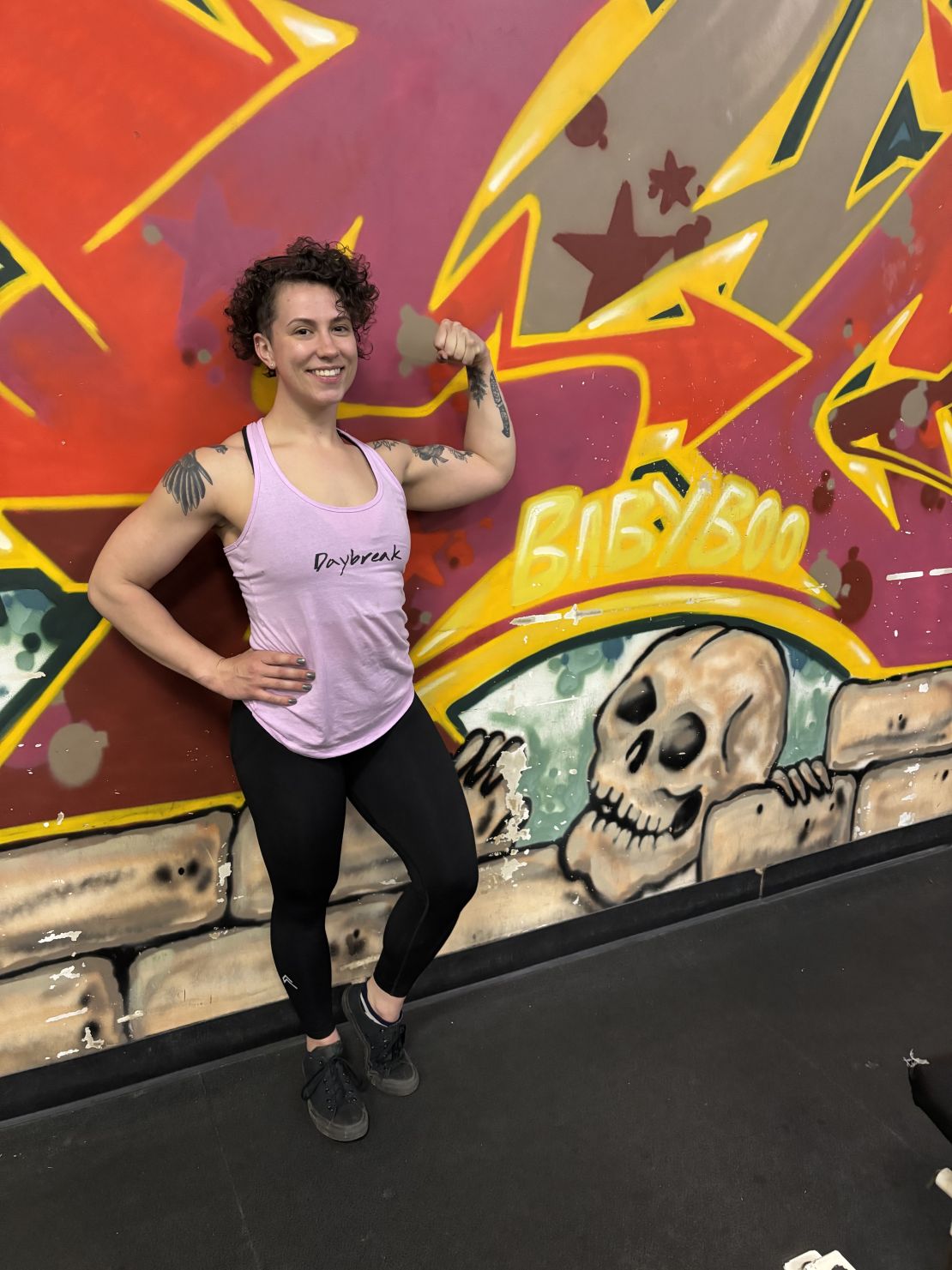 Anna Signorino of Anna Plus Coaching flexing on gym floor in Akron, Ohio—celebrating strength, confidence, and personal transformation through inclusive fitness and powerlifting